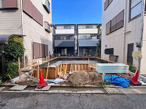 建築中の建物と周辺環境を確認できる一枚。前面の道路や隣接する住宅との位置関係が分かり、完成前の現地の様子を具体的にイメージしやすい写真です。