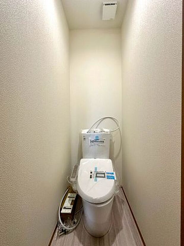ウォシュレットのついた温水洗浄便座のトイレです。暖房便座、脱臭、乾燥機能などを搭載し、トイレットペーパーの使用量を減らして清潔を保ちます。温かみのある壁紙で落ち着く空間です。