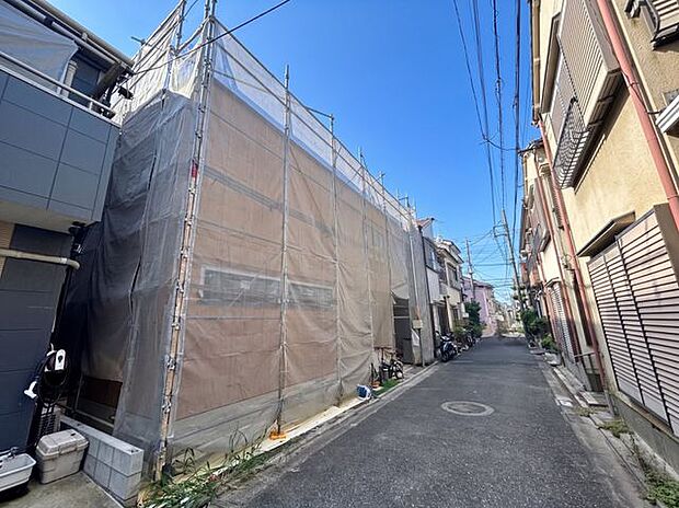 建築中の建物と前面道路を一緒に確認できる写真。実際の現地の雰囲気や道路との位置関係、周辺の建物との距離感などもイメージしやすい一枚です。