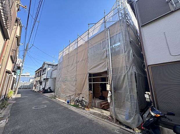 建物周辺の道路状況と建築中の外観を確認できる写真。現地の街並みや接道状況など、物件の周辺環境を検討する際にも参考になる写真です。