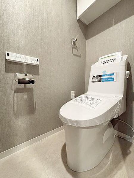 ウォシュレットのついた温水洗浄便座のトイレです。扉付きの吊戸棚もあり、掃除用具や予備のトイレットペーパーなども隠してたっぷり収納できます。