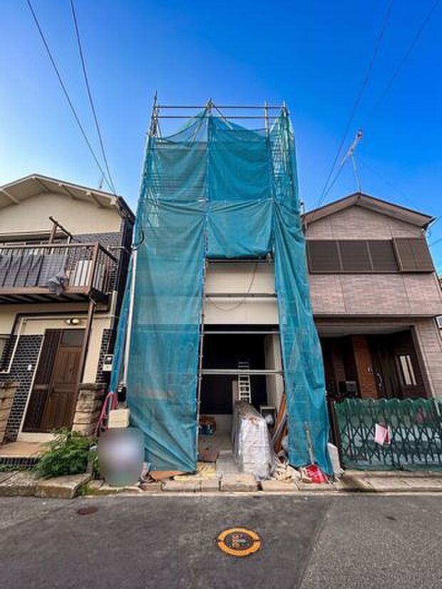 建築中の建物と前面道路の様子を確認できる現地写真。道路幅や周辺の住宅との位置関係も分かりやすく、建物完成後の街並みや暮らしをイメージする際にも参考になる一枚です。