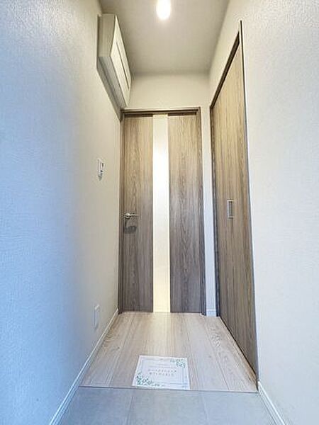 白を基調とした明るく清潔感のある玄関。廊下には収納スペースも設けられており、生活用品をすっきり整理しやすい仕様です。室内へ続く動線もシンプルで、毎日の出入りが快適にできます。