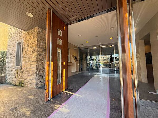 木目調の扉と石調の壁を組み合わせた、落ち着きのあるエントランスです。屋内へ続くアプローチもきれいに整えられており、住まいへ帰るたびに心地よく迎えてくれる空間です。