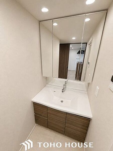 大きく見やすい三面鏡で清潔感ある洗面台。収納も多く、コスメ等もスッキリと仕舞えます。※現況写真にAIによる画像処理（家具等を消す）がされています。