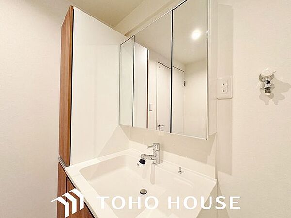 大型の鏡（または三面鏡仕様）を備えた、機能的なシステム洗面化粧台。身支度がしやすい広い洗面ボウルや、散らかりがちな洗面小物をスッキリと隠して片付けられる充実の収納スペースが完備されています。