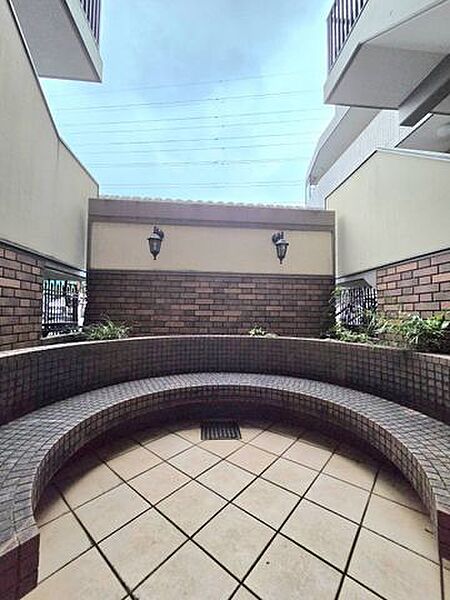 建物のエントランスはタイル張りで落ち着いた雰囲気。植栽や照明もバランスよく配置され、訪れる人を気持ちよく迎えてくれます。住まいの第一印象を上品に演出する整えられた空間です。