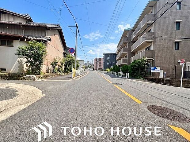 前面の道路は通行や駐車の際に余裕がある広さです。運転が苦手な方も落ち着いて駐車できます。（空の加工を生成AIで行っています）