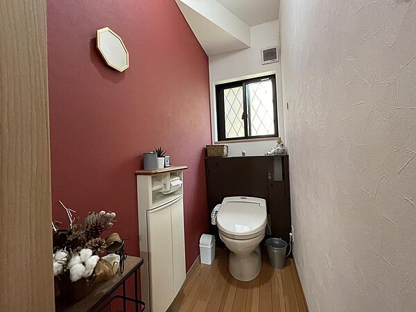 アクセントクロスがおしゃれなトイレは、快適な温水洗浄便座付き。小物を飾れる棚も便利で、清潔感のある空間です。
