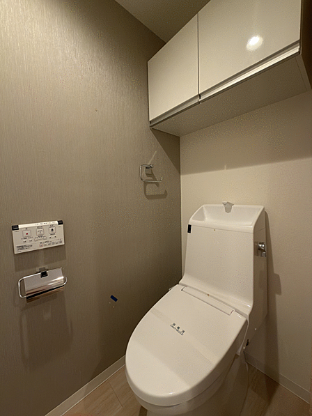 温水洗浄便座を備えた清潔感のあるトイレ。上部収納付きでストック用品もすっきり収納できます。