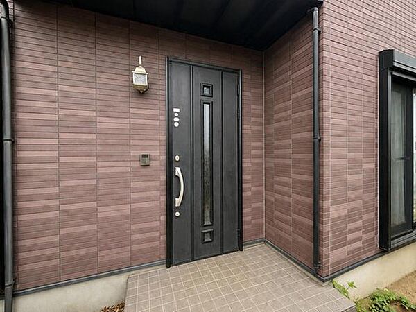 レンガ調の外壁と屋根付きポーチが調和した、雨の日も安心の玄関です。