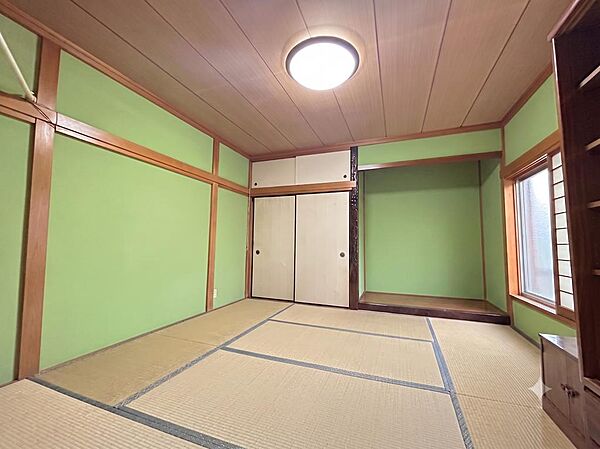 落ち着いたグリーンの壁と畳が印象的な和室。床の間・地袋・天袋の収納が揃い、来客対応や仏間としても使いやすい設えです。