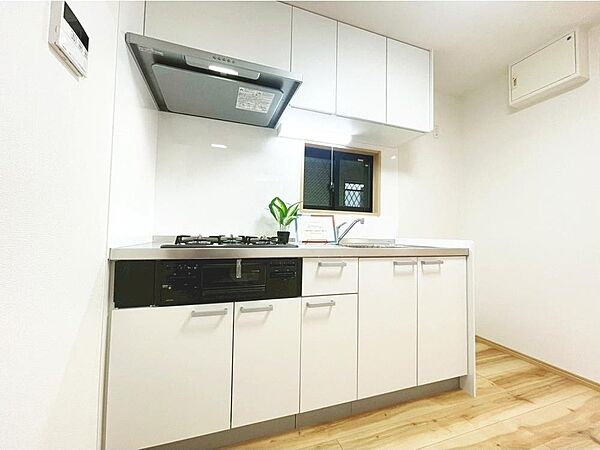 収納豊富なシステムキッチンで、調理器具や食器もすっきり整理。広めの作業スペースで、毎日の料理がはかどります。白を基調とした明るいキッチンは清潔感があり、窓付きで換気も良好。