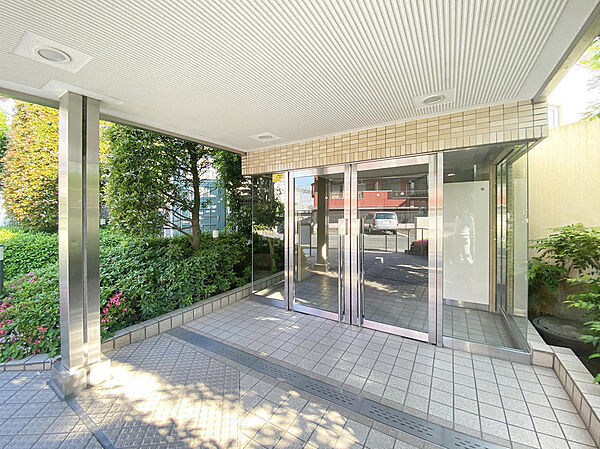 屋根付きの広いエントランス前スペースは、雨の日の出入りにも便利。周囲を緑に囲まれた心地よいアプローチです。