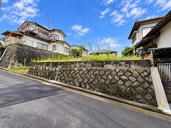 前面道路から敷地を正面から確認できる一枚。道路との高低差があり、石積み擁壁の上に広がる約60.35坪のゆとりある敷地です。