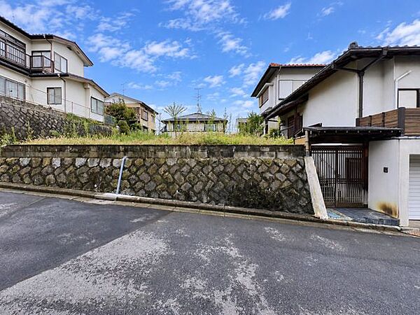 前面道路に面した敷地を正面から確認できる写真。石積みの擁壁と高低差が特徴的で、土地の形状や現地の雰囲気をしっかり確認できます。