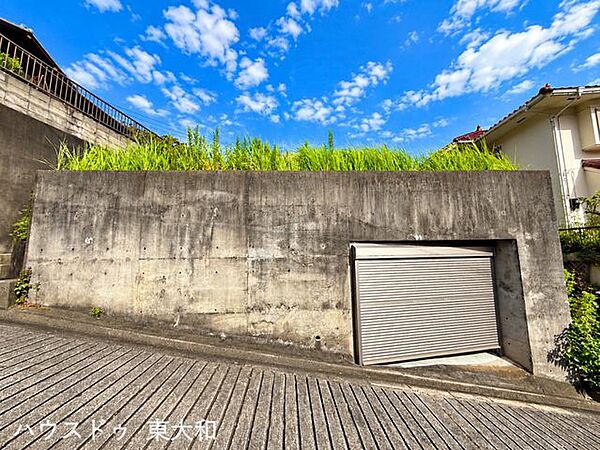 前面道路から見える掘込車庫付きの土地。シャッター付きで、大切な車を雨風から守れるスペースが確保されています。敷地の高低差を活かした特徴的な土地です。