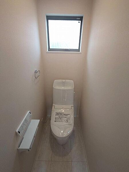 温水洗浄機能付きで季節を問わず快適に過ごせるトイレは、淡い色みのクロスで柔らかな印象です。