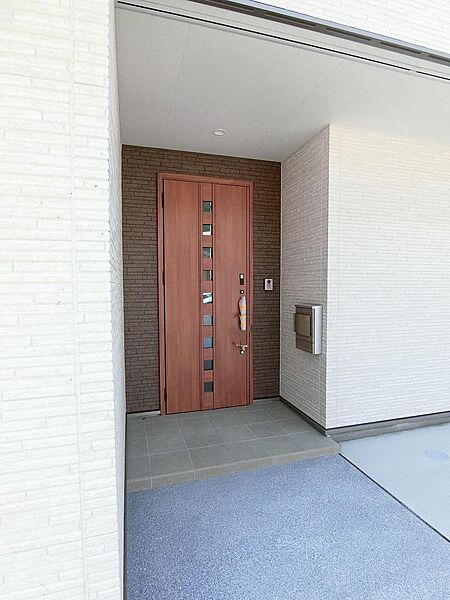 白い外壁にブラウンのドアがアクセント♪屋根のある玄関ポーチで雨の日の出入りも落ち着いてできます。