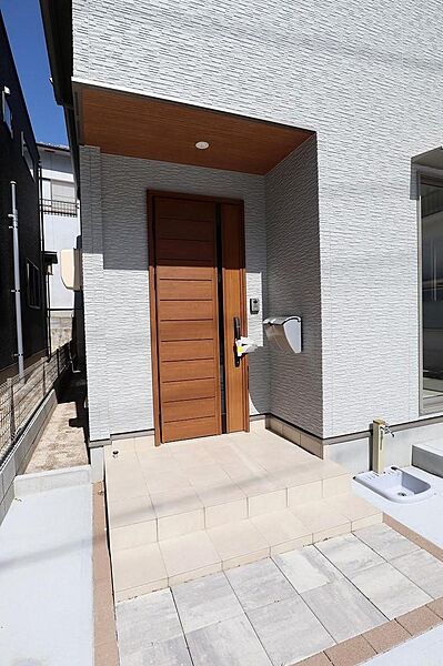 柔らかな色味の外壁にブラウンのドアが際立つ玄関周りです。