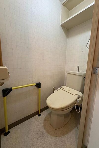 立ち座りをサポートする手すりを完備し、高齢者・介護が必要な方にも安心のトイレ設計。温水洗浄便座付きで快適性も確保されています。上部収納棚でトイレ用品もすっきり整理可能!