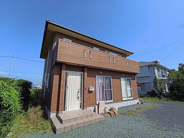 側道路に面し、陽光を全身に浴びる明るい外観。清潔感のあるデザインは、周囲の穏やかな住環境と調和する。広い敷地を活かしたアプローチが、住む人とゲストを優しく迎え入れる家の顔。