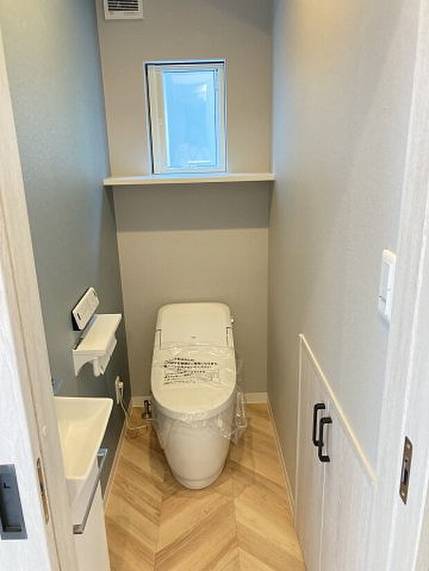 【トイレ】1階トイレ ヘリボーンの床とアクセントクロスがかわいい！収納もあるのでトイレットペーペーも入れておけますね。