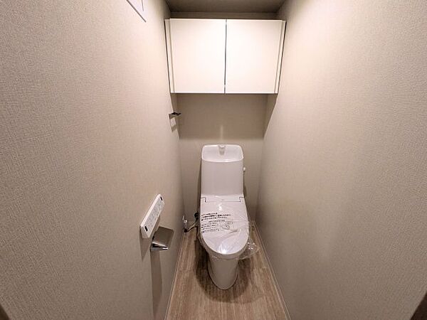 清潔感溢れる温水洗浄便座付きトイレ。上部に吊戸棚がありトイレットペーパーなどを隠して収納できます。