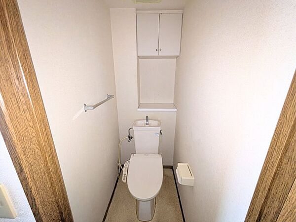 上部に棚を備えた快適なトイレ空間。トイレットペーパーや清掃用品をすっきりと隠して保管できます。