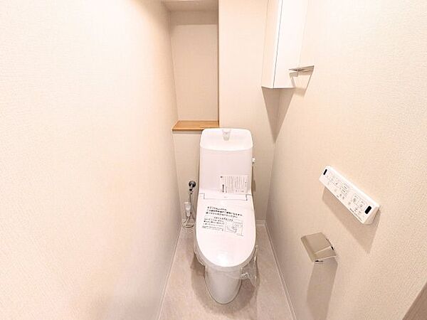 温水洗浄便座を完備した快適なトイレ空間です。上部にはトイレットペーパー等をしまえる棚を備えています。