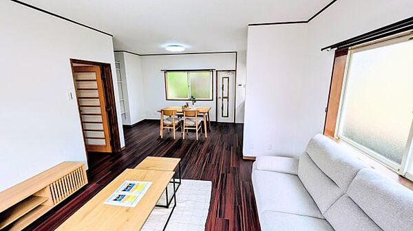 落ち着いたダークブラウンの床と白い壁が調和する、開放的でゆとりあるリビングダイニングです。