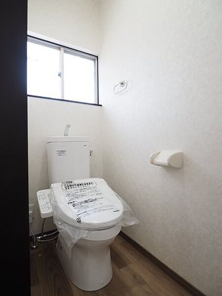 温水洗浄便座を備えた清潔感のあるトイレ。小窓から光が差し込み、爽やかな空間を保ちます。
