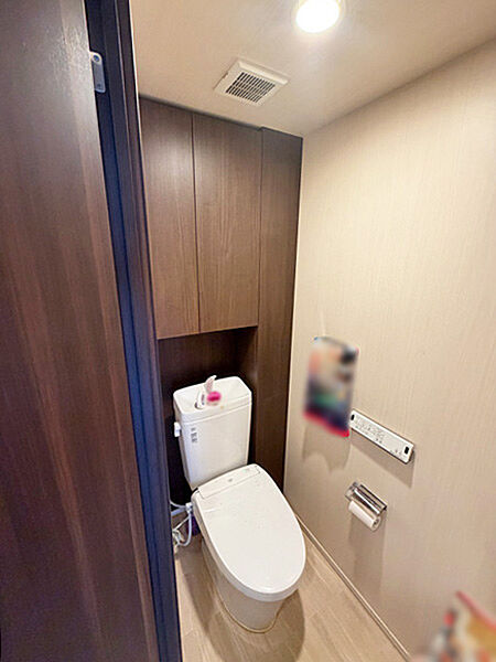 温水洗浄便座付きトイレ。上部収納を備えた、清潔感のある快適な空間です。