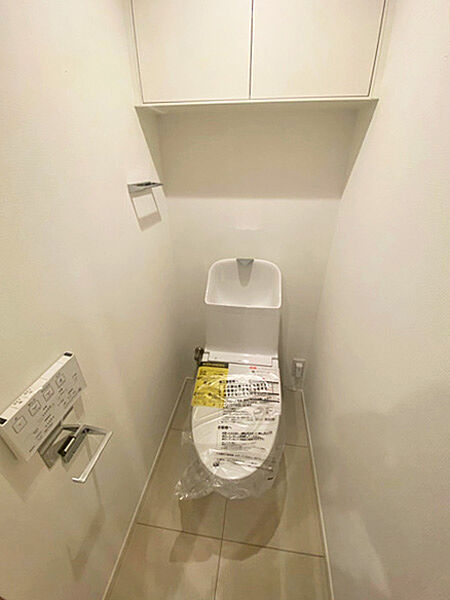 上部収納を備えた機能的なトイレ空間。すっきりとした印象が魅力です。