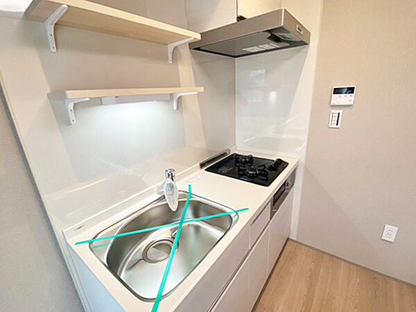 シンプルで使いやすいシステムキッチン。収納棚を備えており、調理器具や食器類をすっきり整理できます。