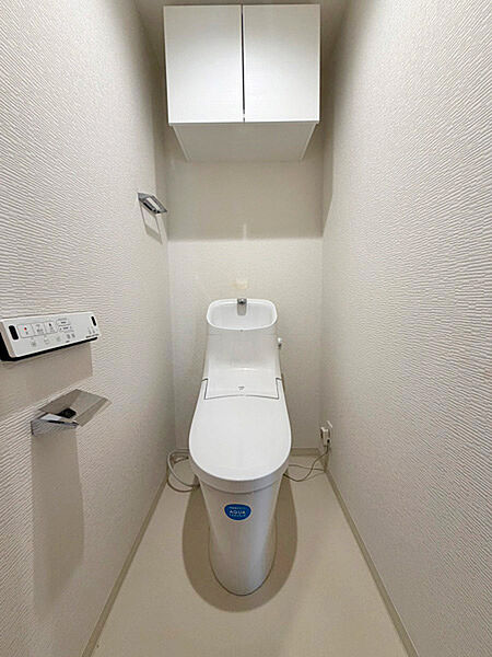 温水洗浄便座付き。上部収納を備えた、清潔感のあるレストルームです