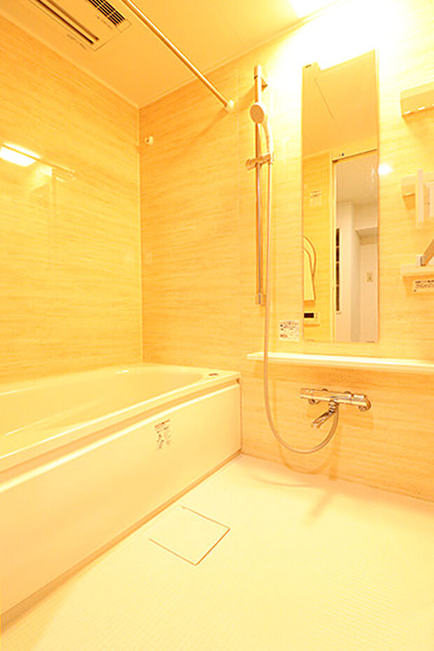 追い炊き機能・浴室乾燥機付きのユニットバス。壁は温かみのある木目風のデザイン。シャワー位置が調節可能