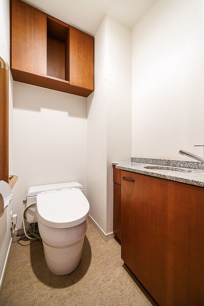 落ち着いた雰囲気のトイレ。独立した手洗い器やトイレットペーパーのストックなどに役立つ吊戸棚付きです。【トイレ】