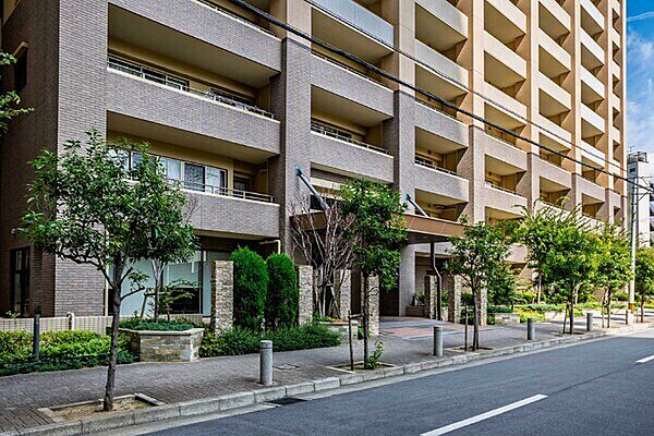 植栽の緑が映えるエントランス。マンションの前には歩道が整備され、お子様やペットとの外出も快適です。【エントランス】