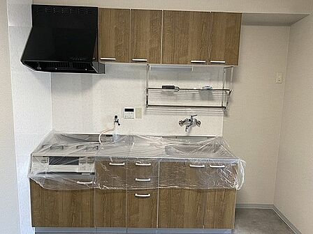 木目調デザインのキッチンは、吊戸棚や下部収納付き。調理器具や食器などがすっきり片付きます。【キッチン】