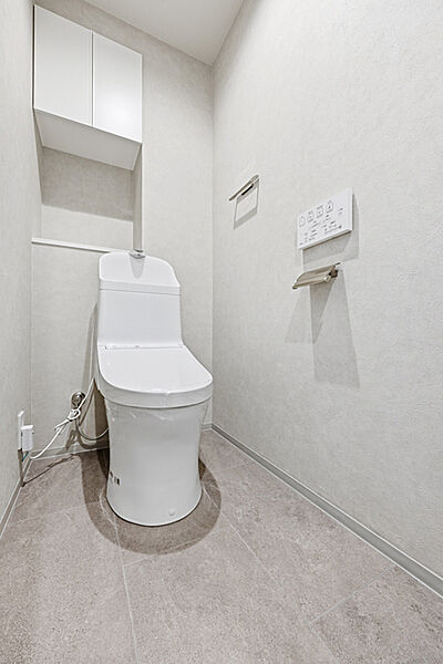 温水洗浄便座付きのトイレです。室内に吊戸棚が備わっており、トイレットぺーパーなどを収納できます。【トイレ】