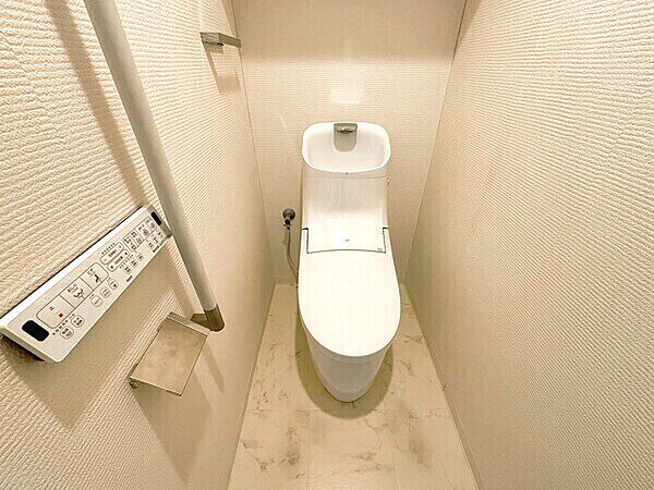 白を基調とした清潔感のあるトイレ。立ち座りをサポートする手すり、タオルハンガーが設置されています。【トイレ】