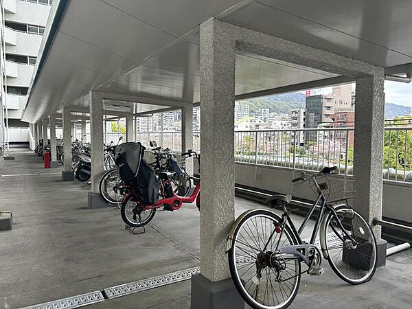 柱と手すりで区切られたスペースには複数の自転車やバイクが整然と並び、雨の日でも安心して駐輪できます。日常の移動や通勤・通学にも便利な環境です。