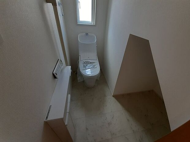 1階のトイレです。階段下部分がちょうどよい収納となっており便利です。