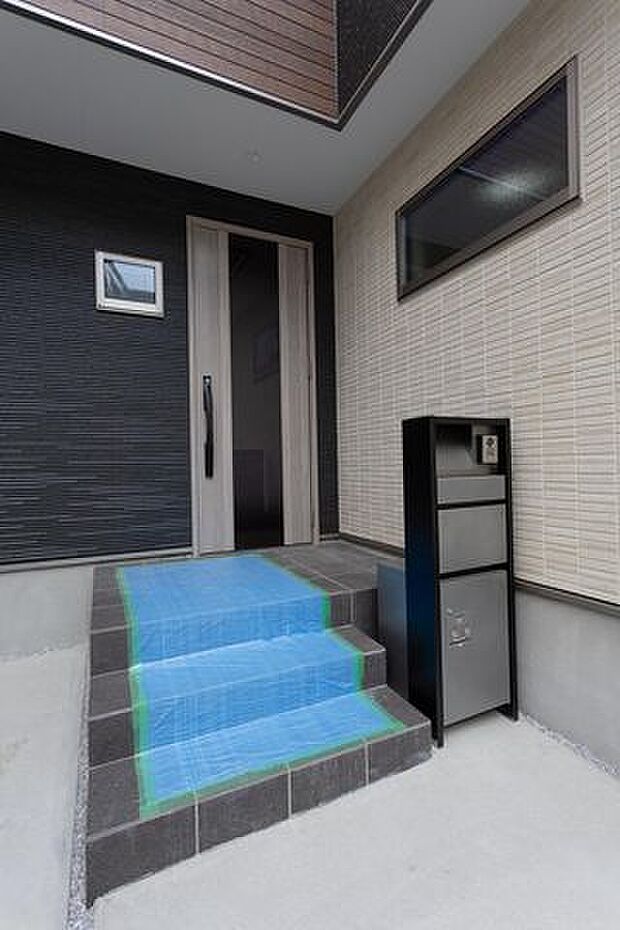 シックなタイルとモダンな木目調ドアが印象的な玄関