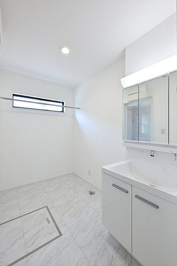 白を基調とした清潔感のある洗面室は、そのまま室内干しもできるハンギングバーを備えています。