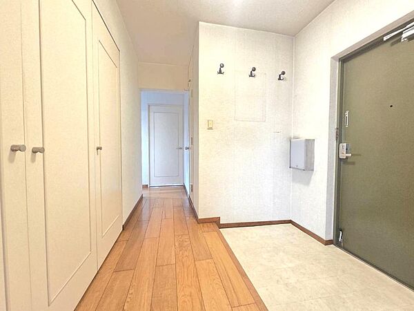 コート掛けのある広々とした玄関です。正面にはゆとりのある収納が備わり、すっきりと片づけられます。