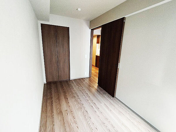 洋室約5帖。白と木目を基調とした暖かみのある明るいお部屋です。