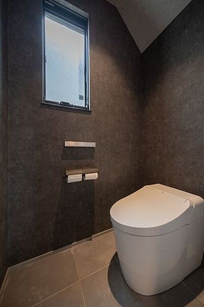 1階トイレはタンクレスタイプを採用。黒のクロスとグレーのタイルを組み合わせた内装です。窓を設け、採光と換気にも配慮されています。