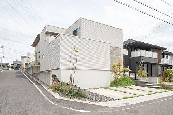 土地面積208.27m2（約63.00坪）。南西側・北西側の道路に接する角地に位置し、開放感のある立地。白を基調とした外観に植栽が彩りを添え、通風や採光にも配慮された住環境です。